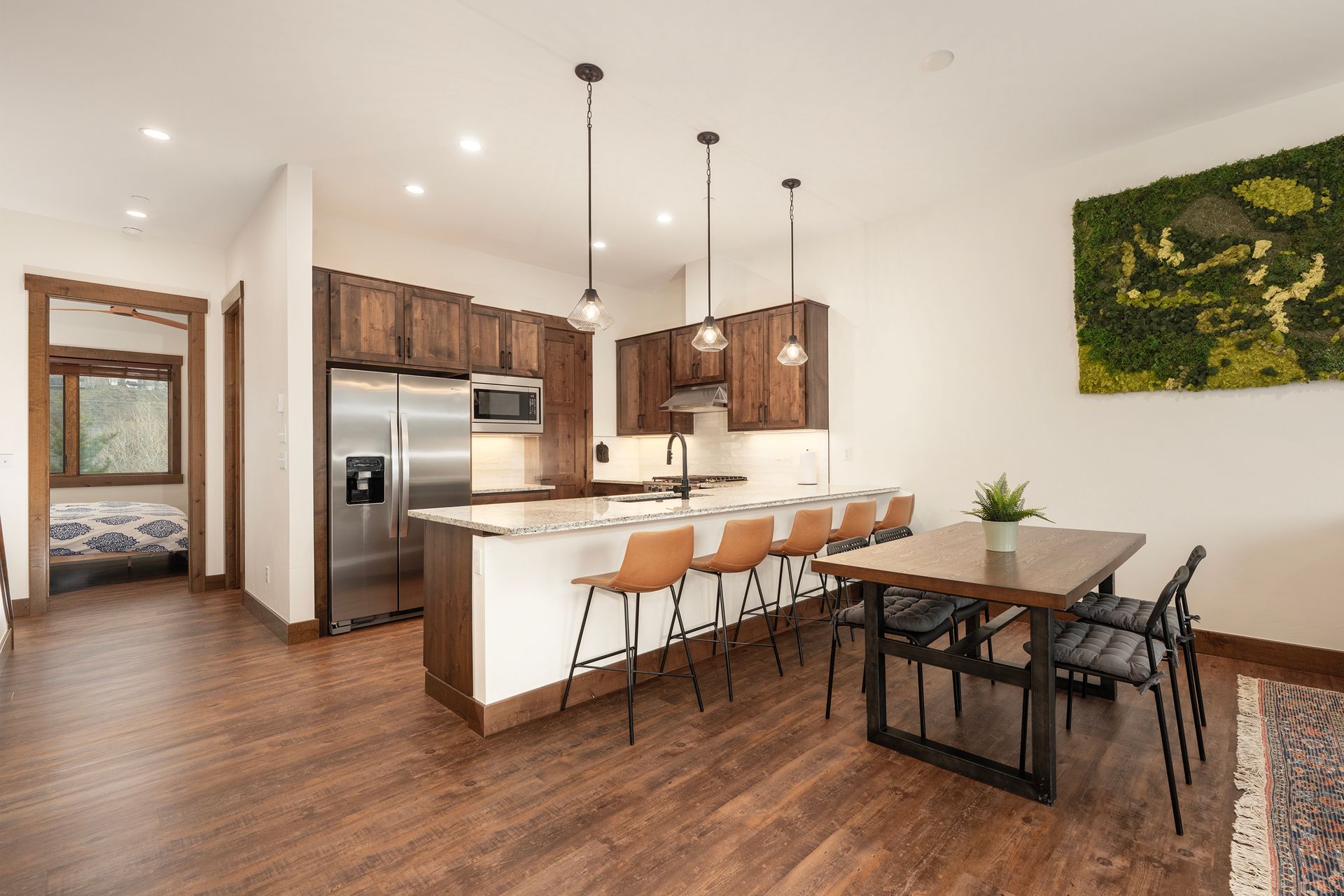 Modern kitchen with brown cabinets, stainless steel appliances, breakfast bar, and dining table.
