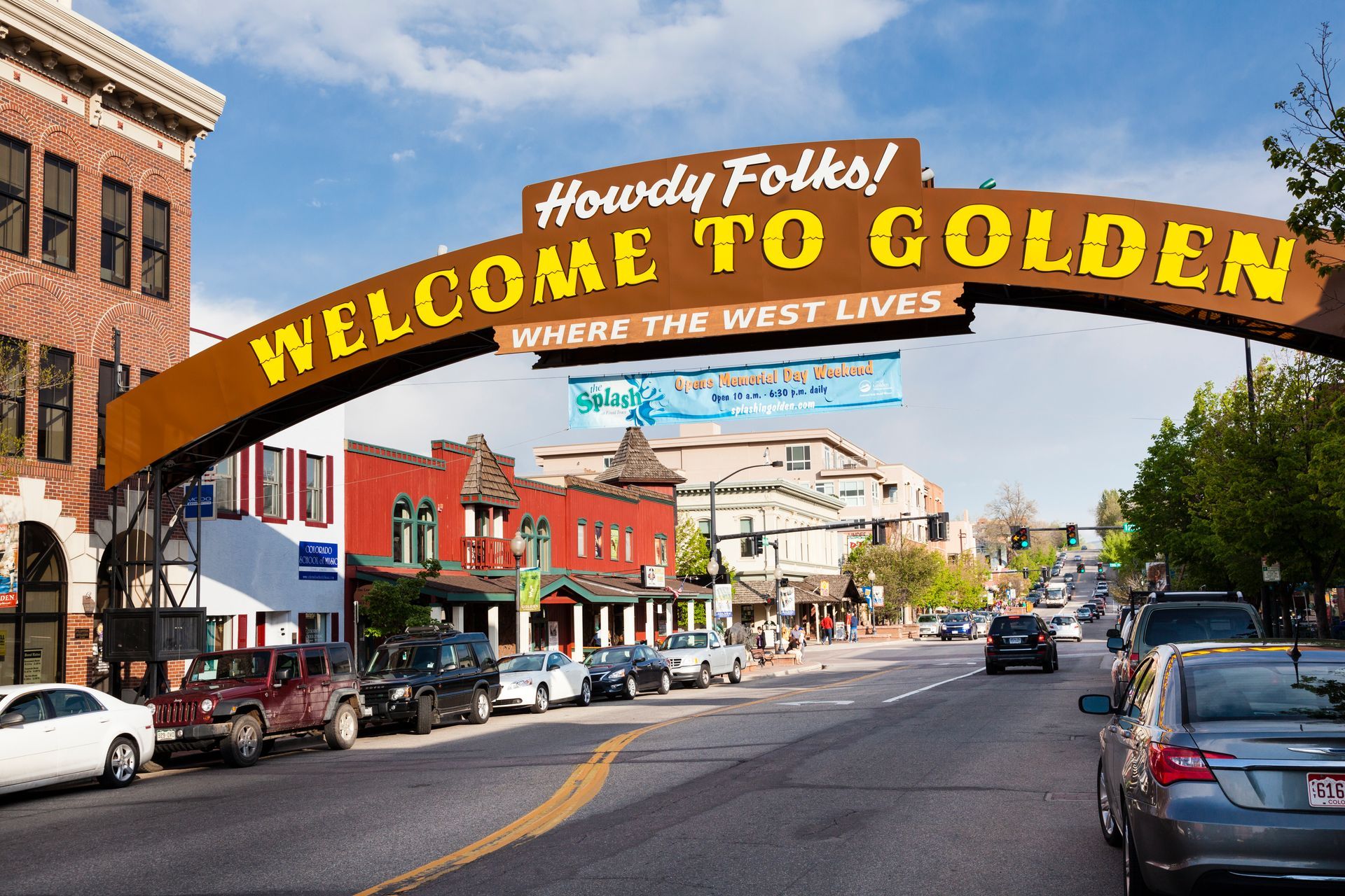 Golden, Colorado welcome arch over a downtown street with shops and parked cars.