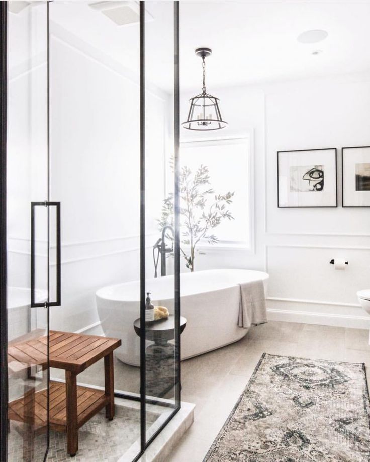 Modern white bathroom with shower, soaking tub, and a decorative rug.