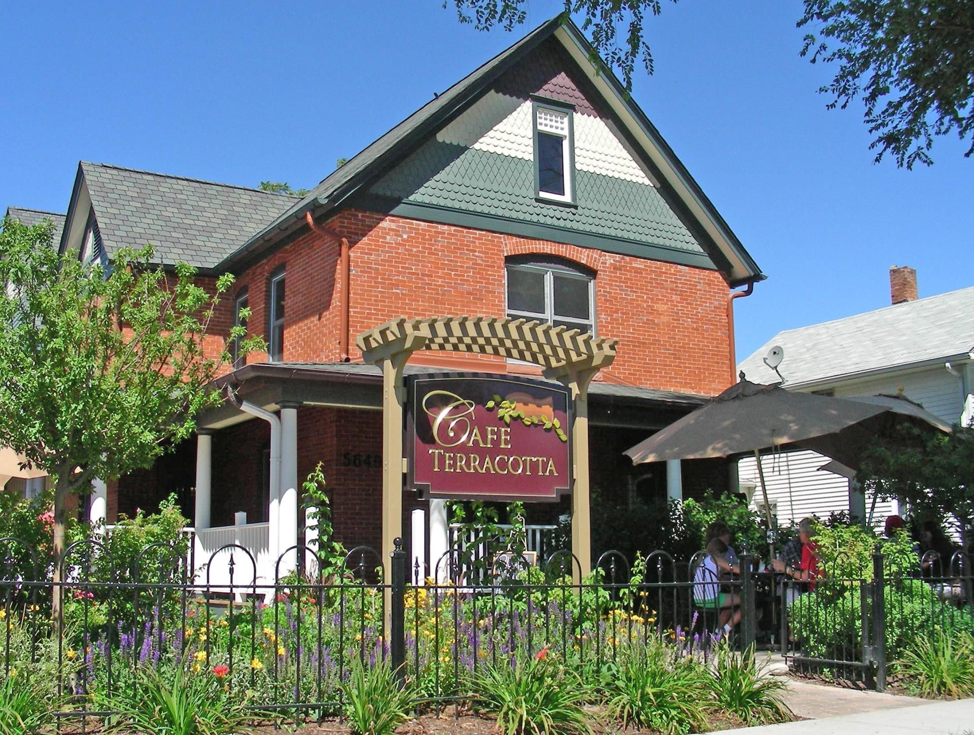 Cafe Teracotta, a brick building, with an outdoor patio, and a flower garden.