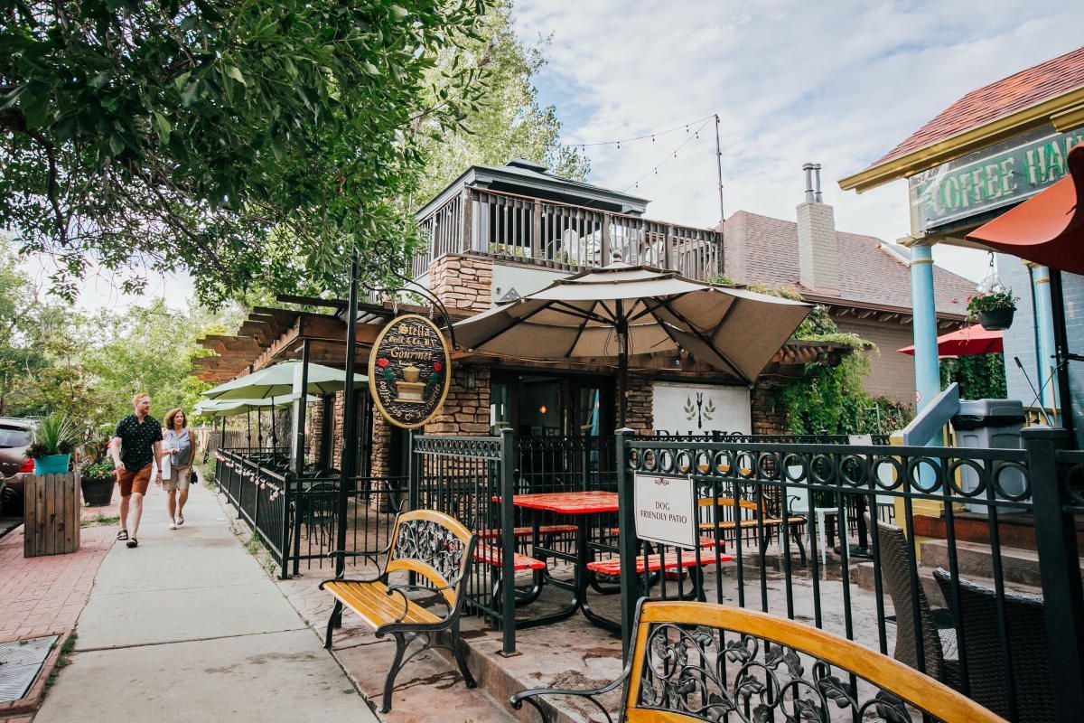Restaurant with outdoor seating, brick facade, and pedestrians on a sidewalk.