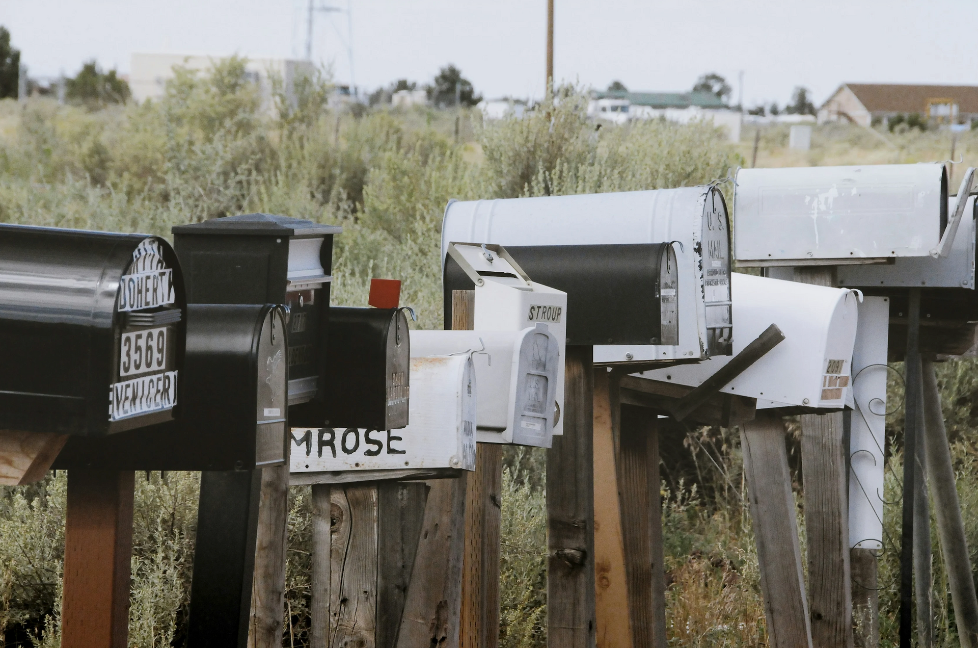 Row of roadside mailboxes on wooden posts in a grassy rural area