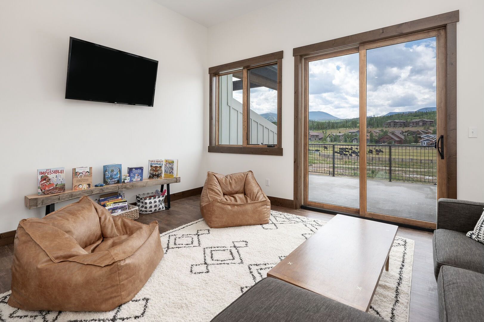 Cozy living room with two bean bag chairs, a rug, and a sliding glass door to a patio with a mountain view.
