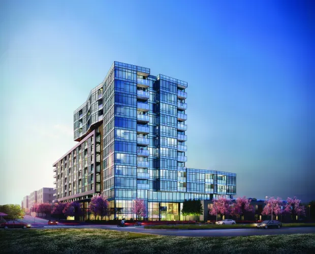 Modern glass building against a blue sky, with balconies, street-level entry, and flowering trees.