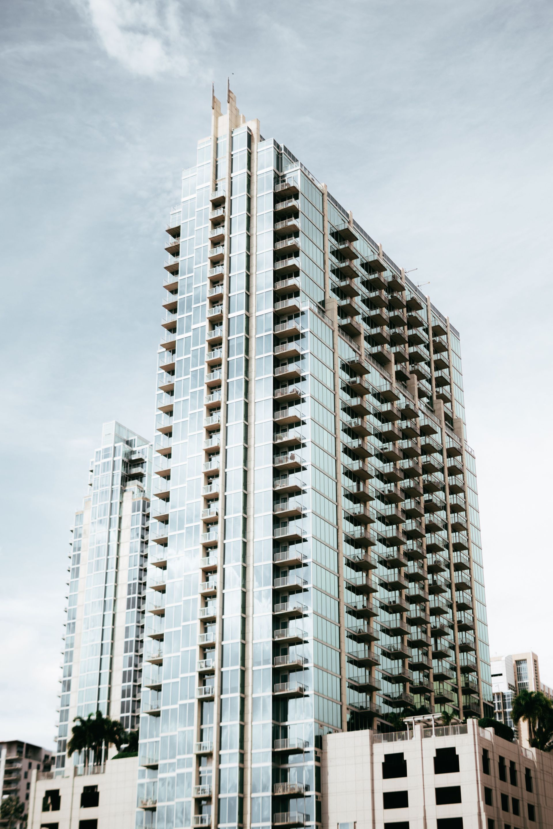 Tall modern high-rise building with balconies against a cloudy sky