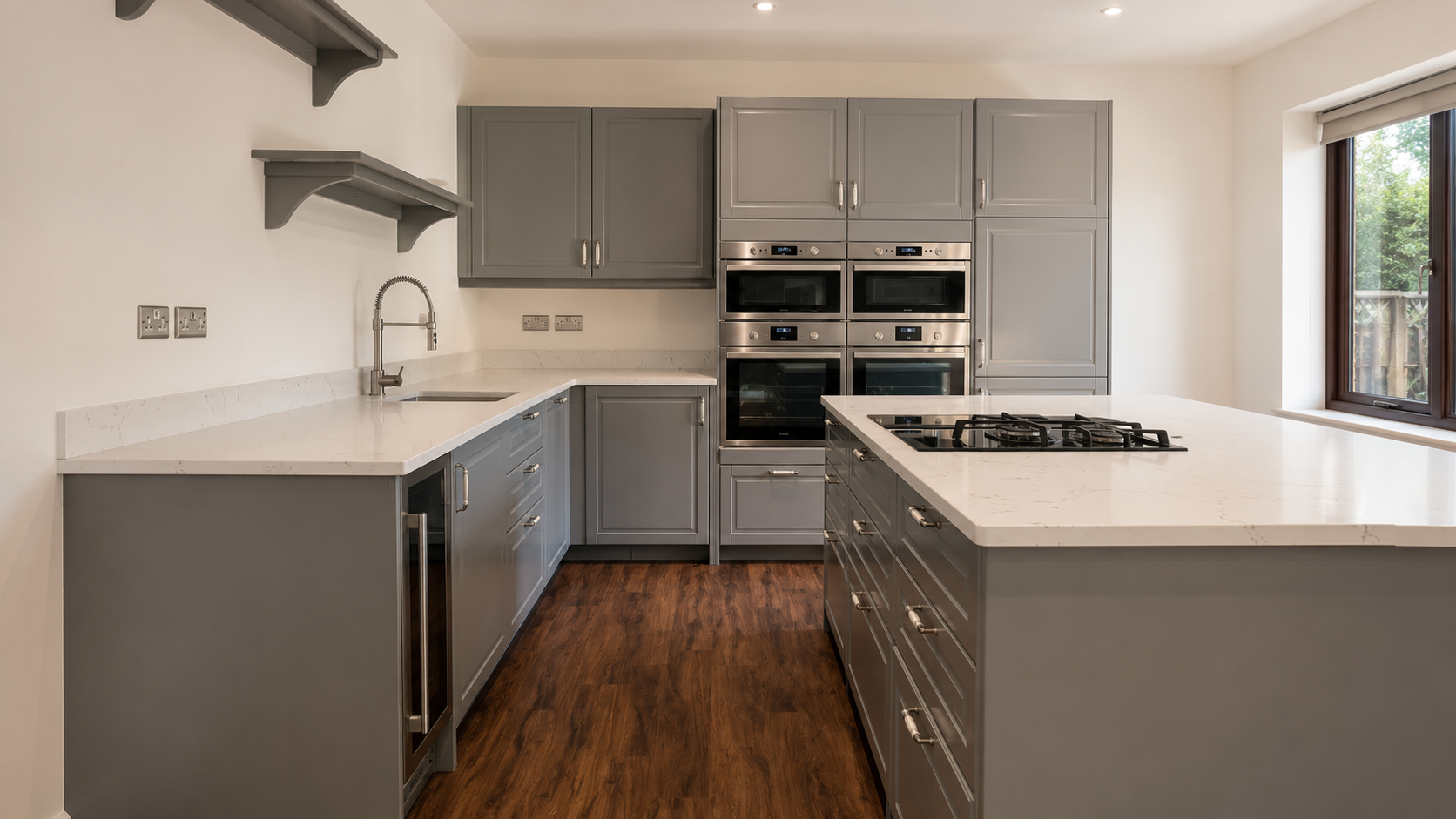 Modern kitchen with gray cabinets, white countertops, wood floor, and built-in stainless steel appliances