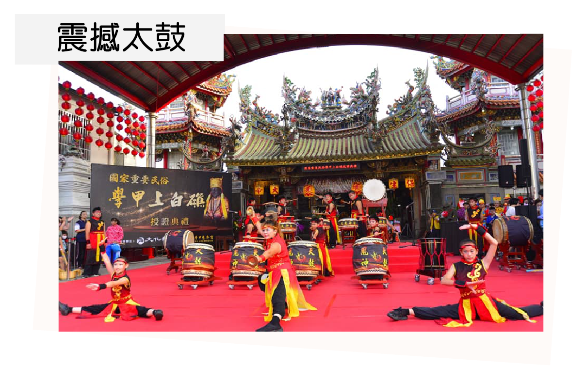 A group of people are playing drums in front of a temple.