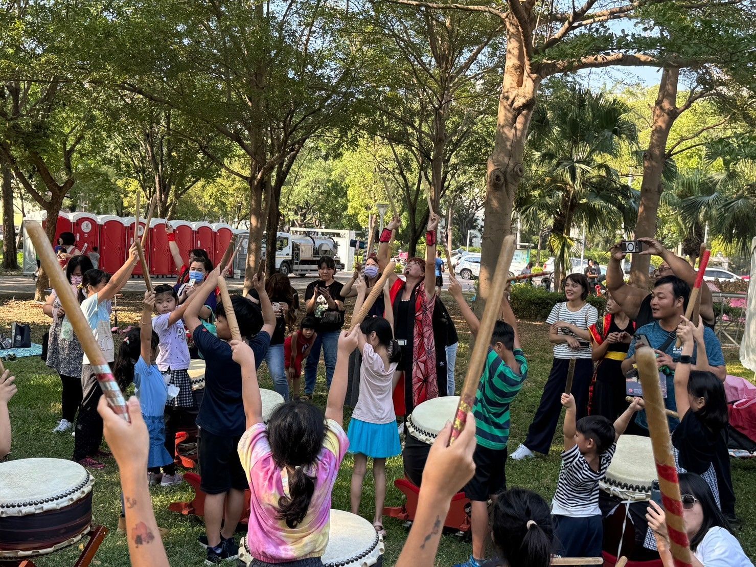 A group of children are playing drums in a park.