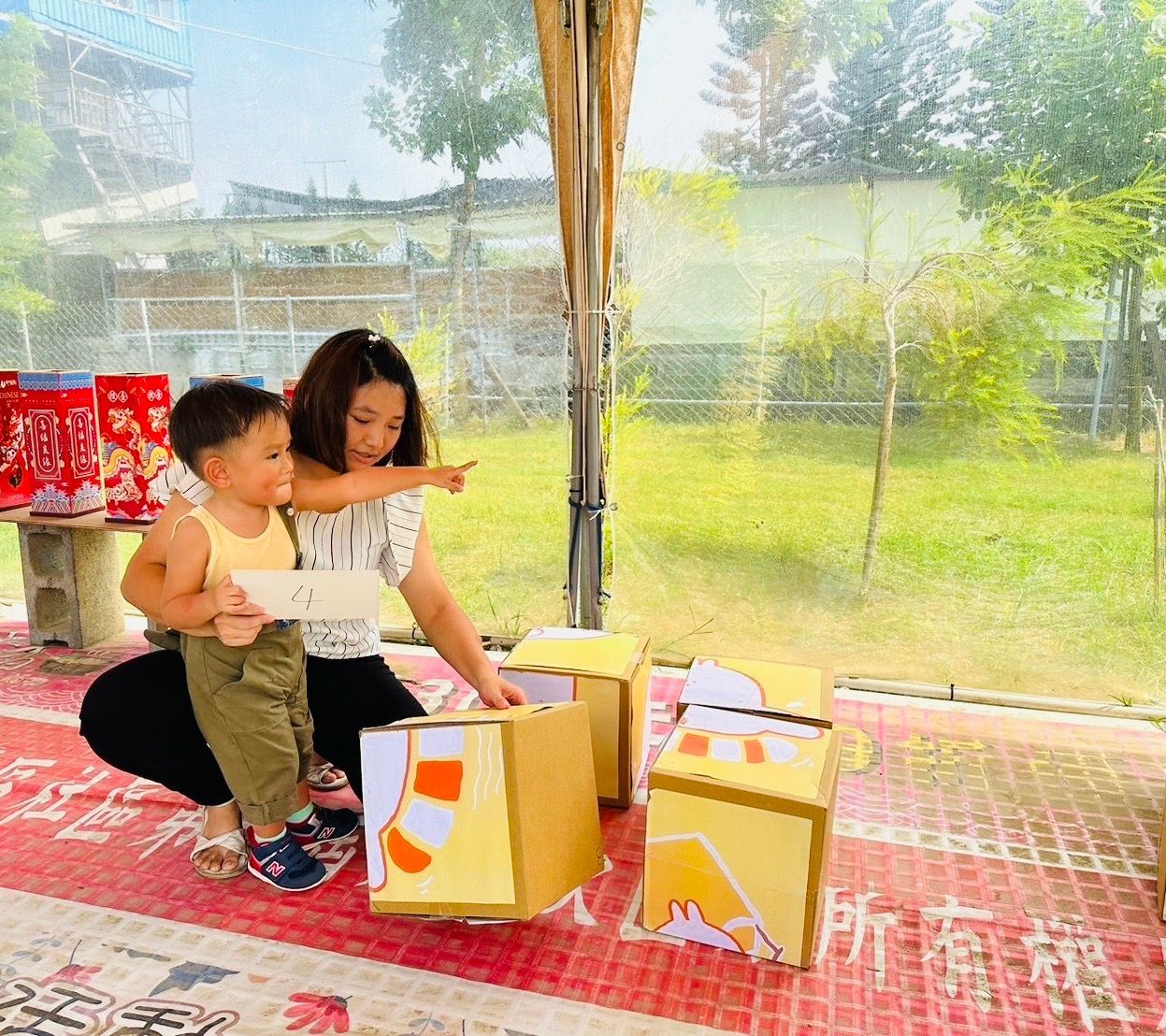 A woman is kneeling down next to a little boy playing with blocks.