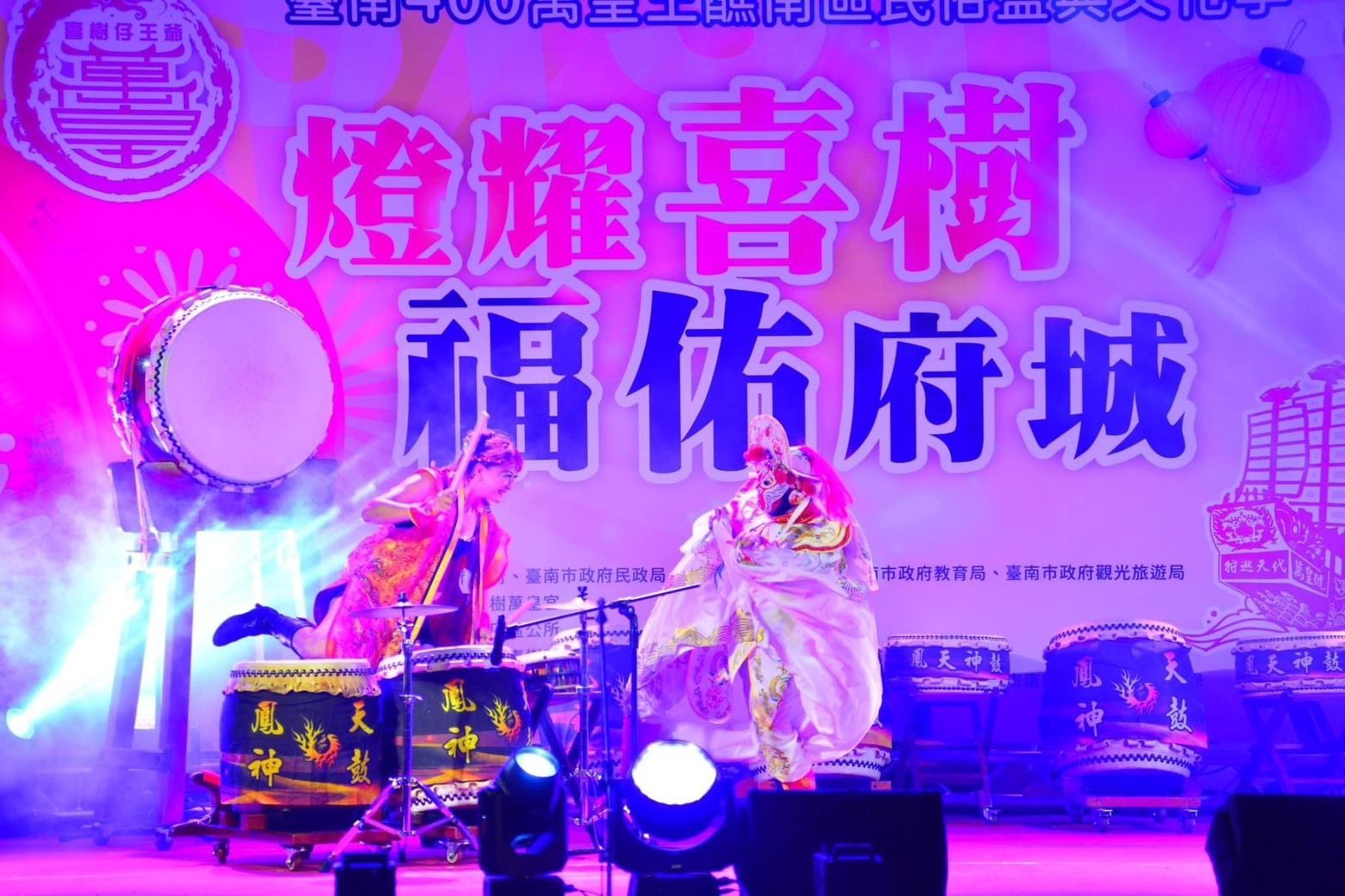 A group of people are playing drums in front of a sign that says ' chinese ' on it