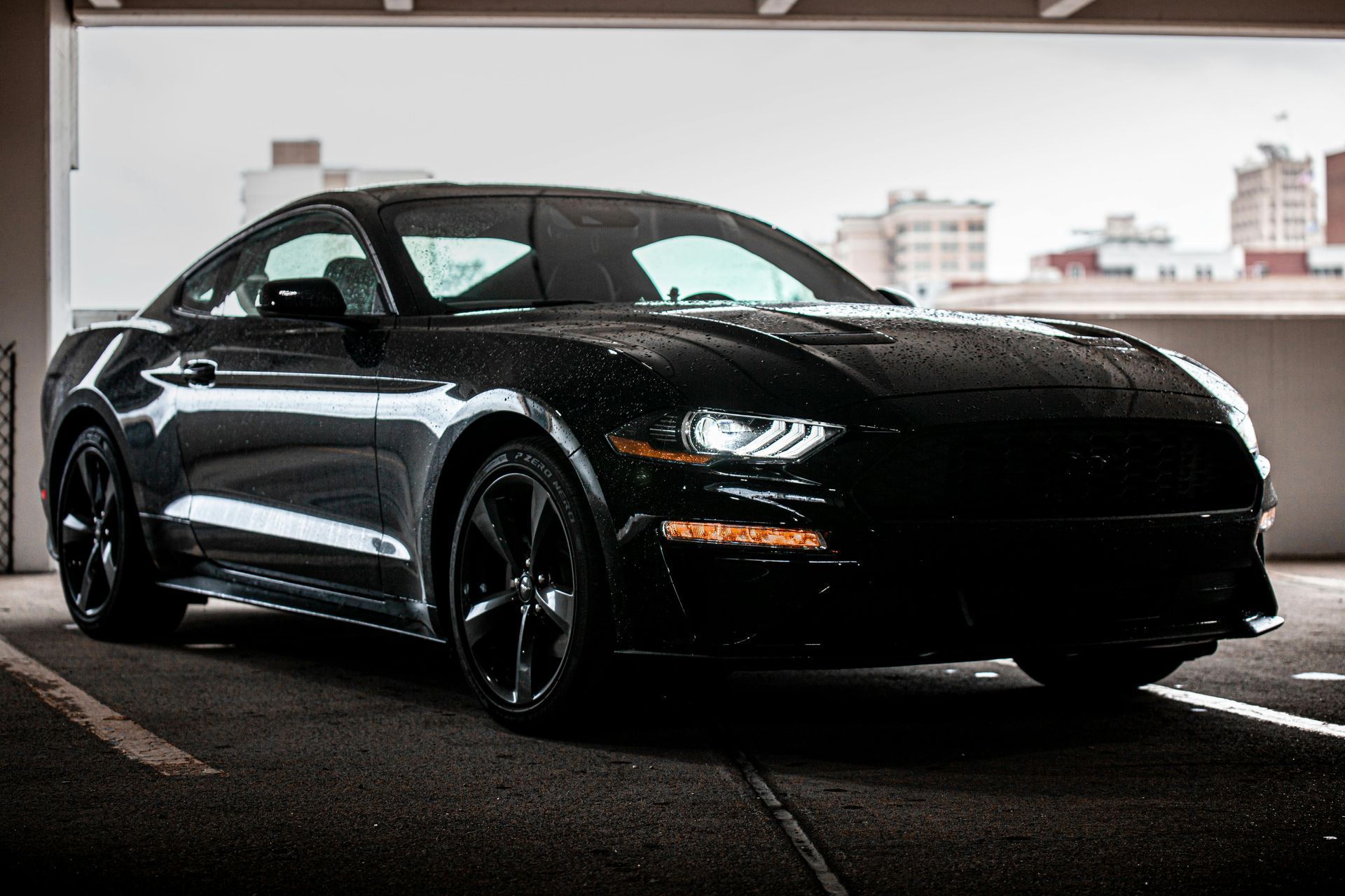 A black ford mustang is parked in a parking garage.
