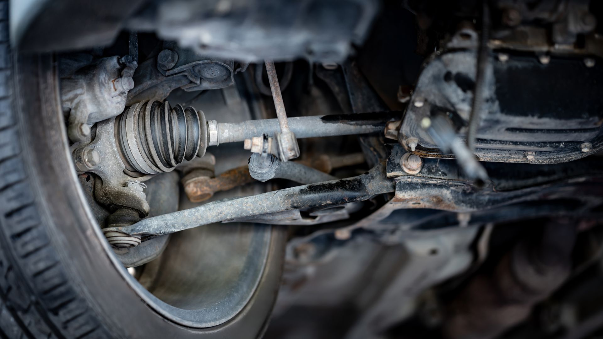 Underside of a car's front wheel, showing suspension components and a driveshaft.