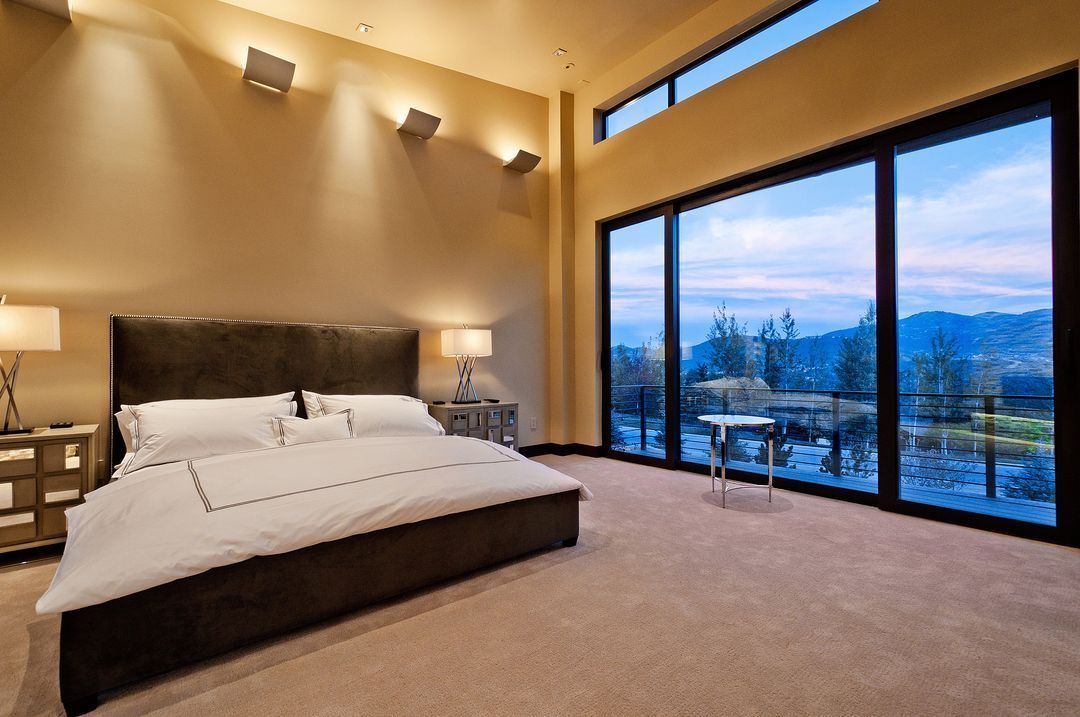 A bedroom with a large bed and lots of windows