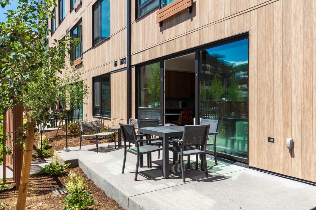 A patio with a table and chairs in front of a building.