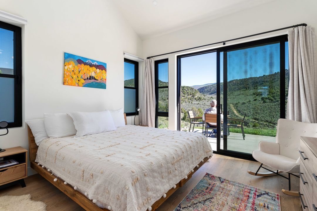 A bedroom with a king size bed , chair and sliding glass doors.