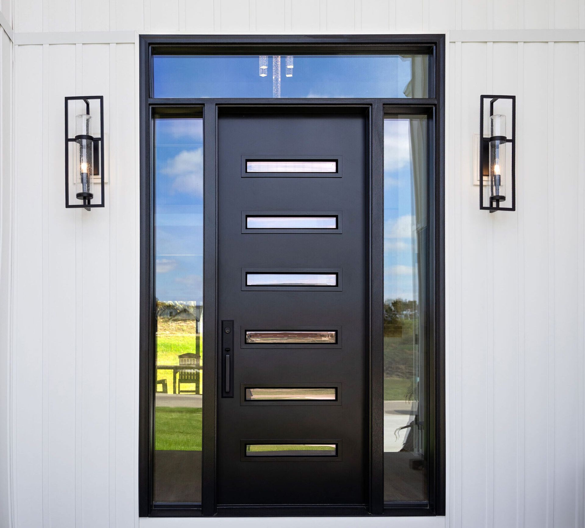 A black front door with a lot of windows on a white wall.
