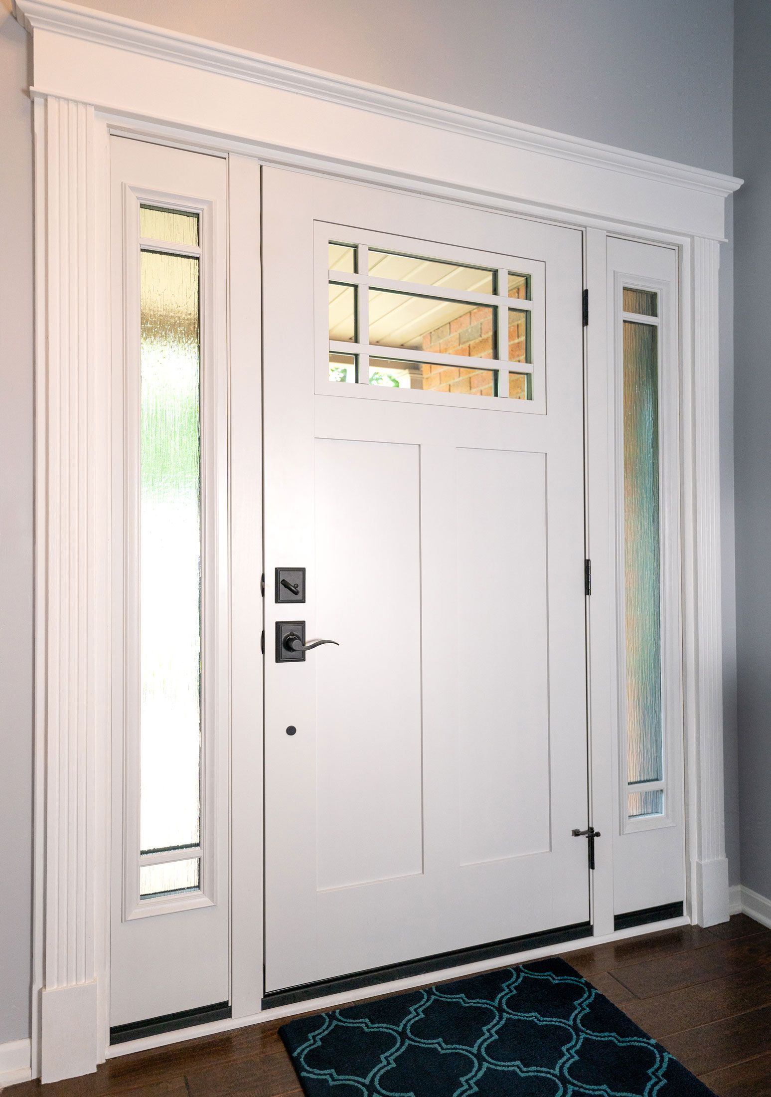 A white front door with a blue rug in front of it.