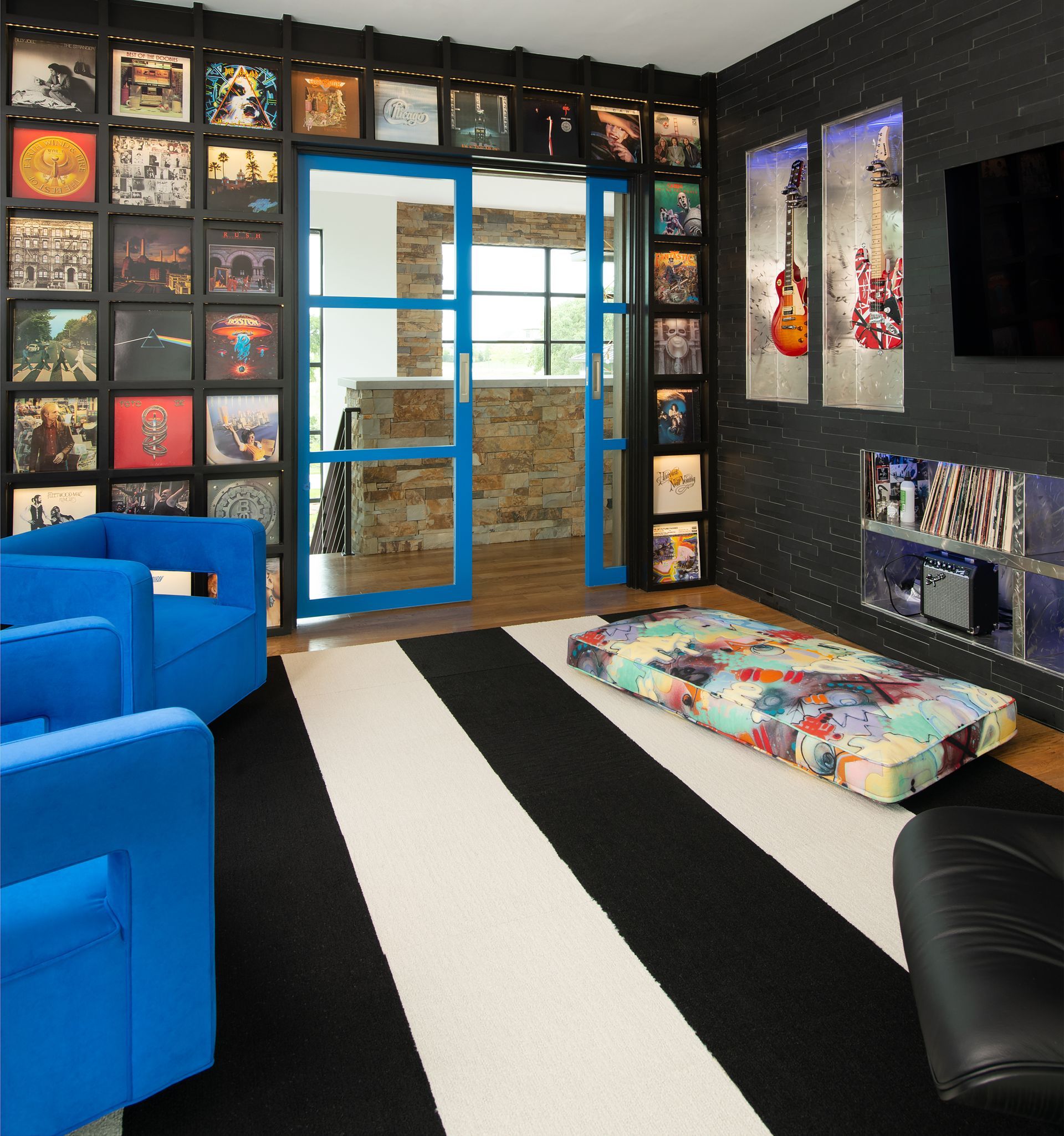 A living room with blue chairs and a black and white rug