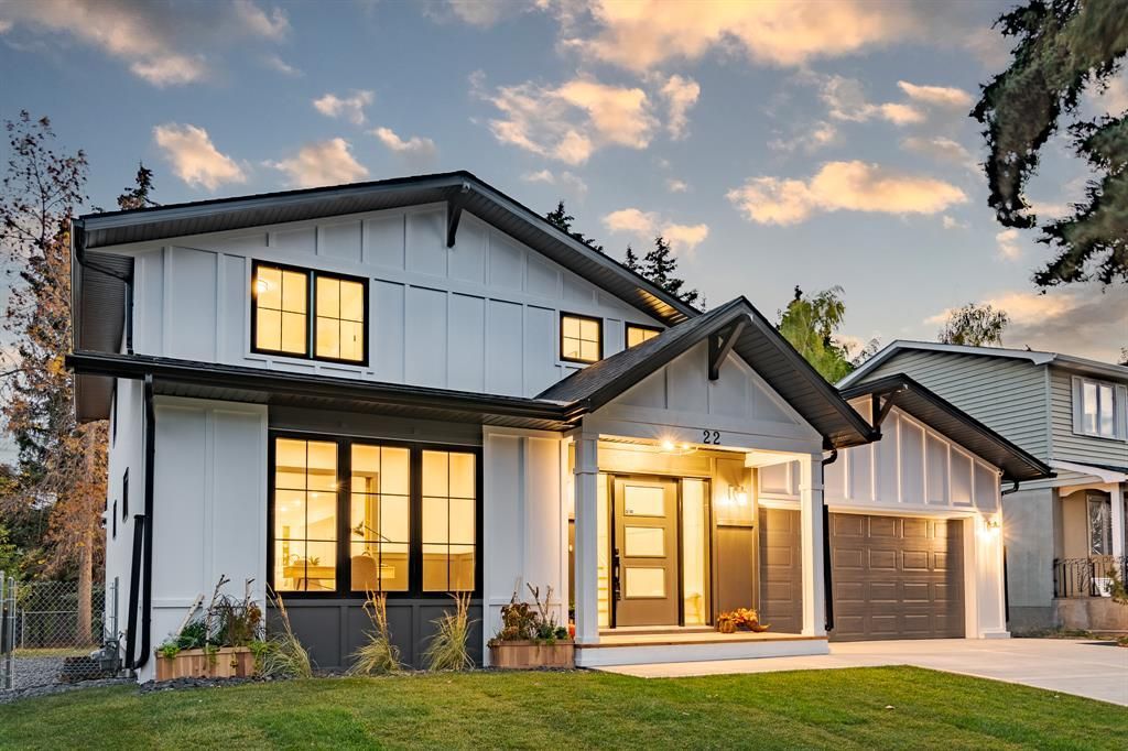A large white and black house with a lot of windows is sitting on top of a lush green lawn.