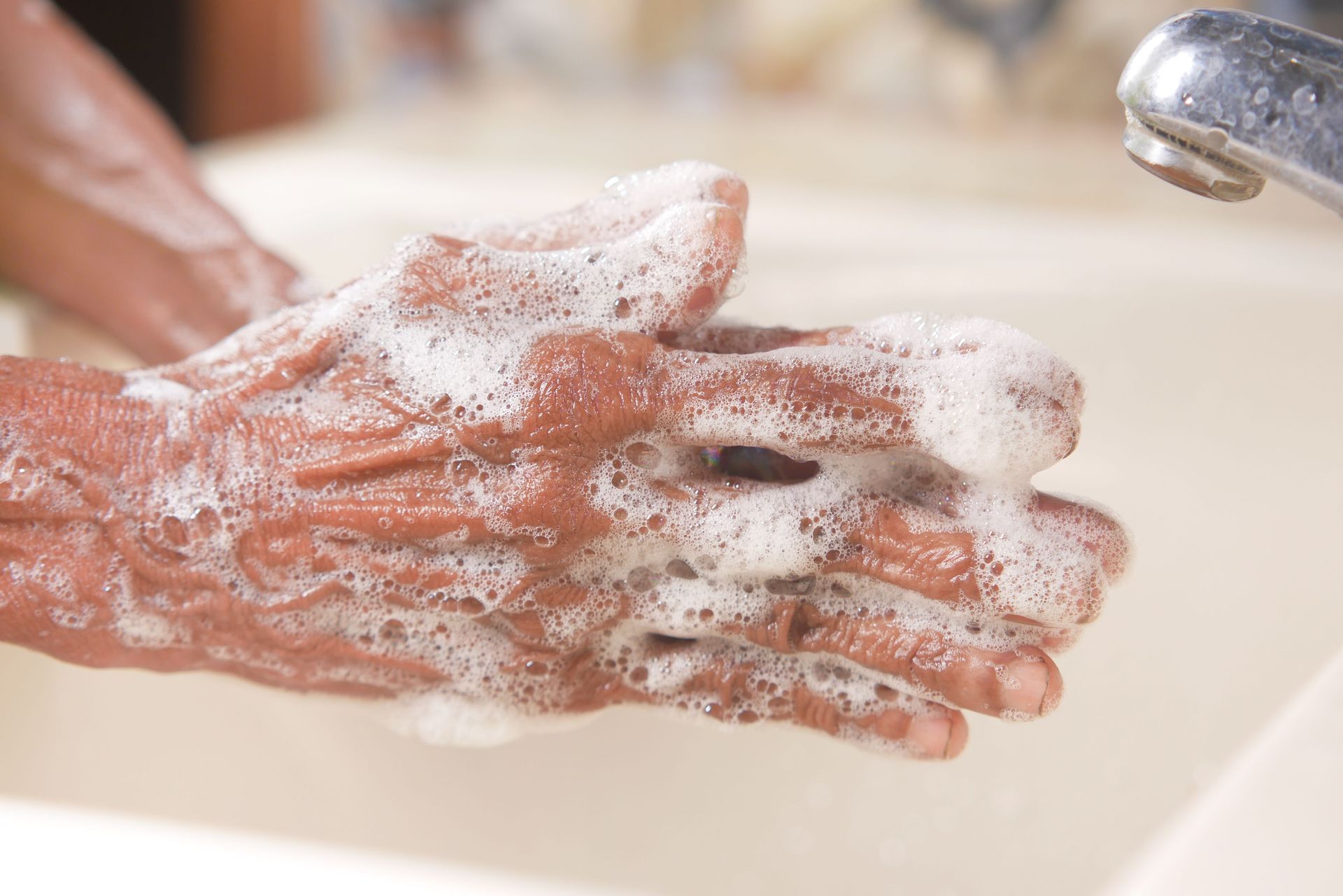 Hands lathered with soap under running water at a sink