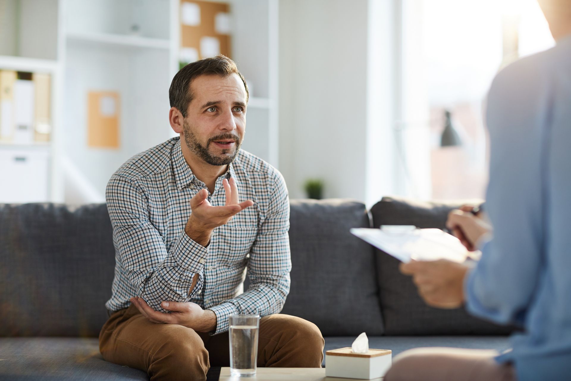A man is sitting on a couch talking to a woman.