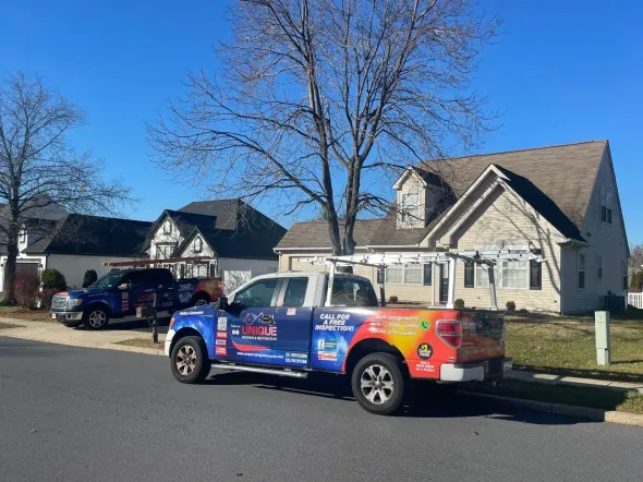 Two company trucks parked on a street in front of houses on a sunny day.