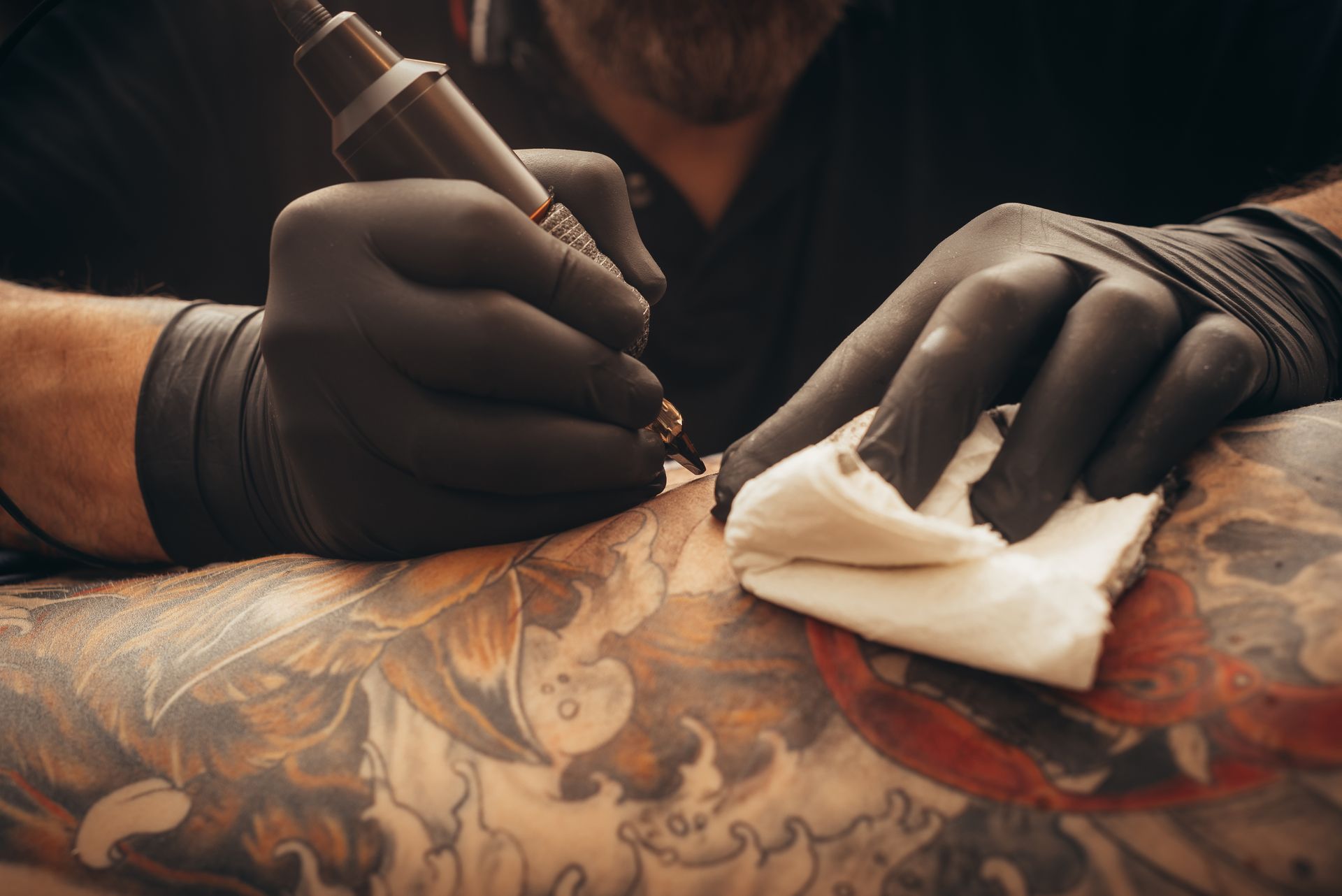 A man is getting a tattoo on a person 's arm.