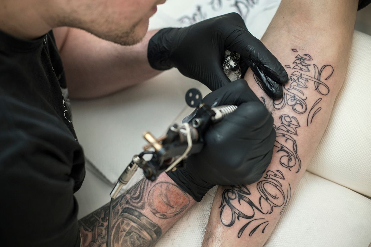 A man is getting a tattoo on his arm.