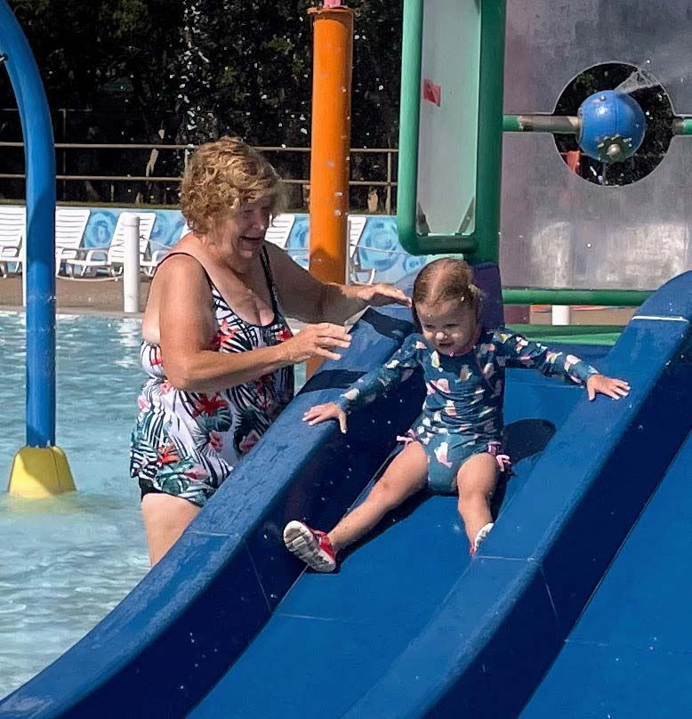 A woman helps a little girl on a slide at a water park