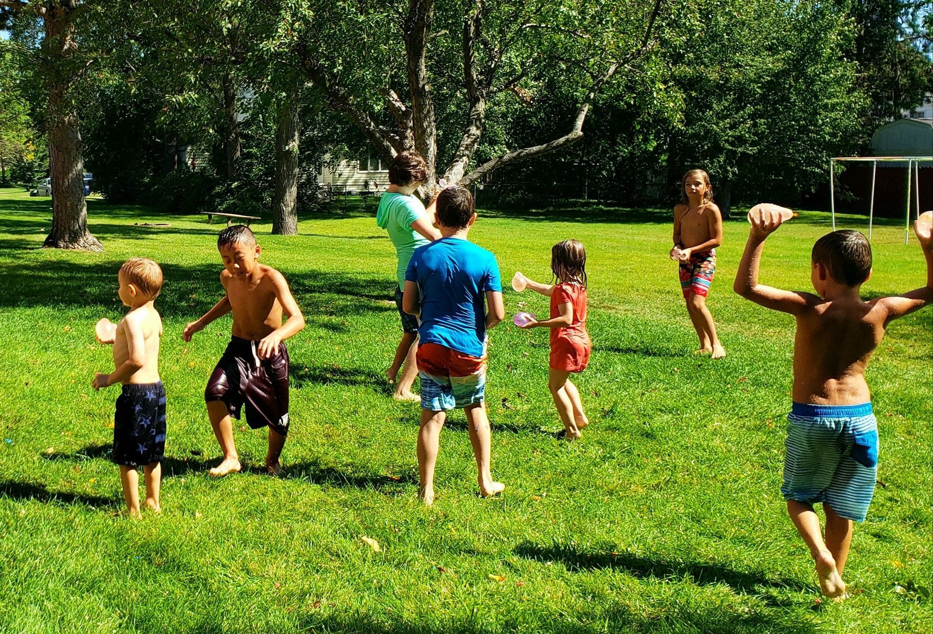 A group of children are playing in the grass in a park.