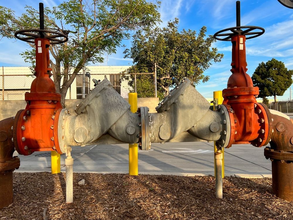 A Backflow Prevention Assembly With Two Red Valves And A Central Metal Unit — ATEC Plumbing Services in Lake Macquarie, NSW