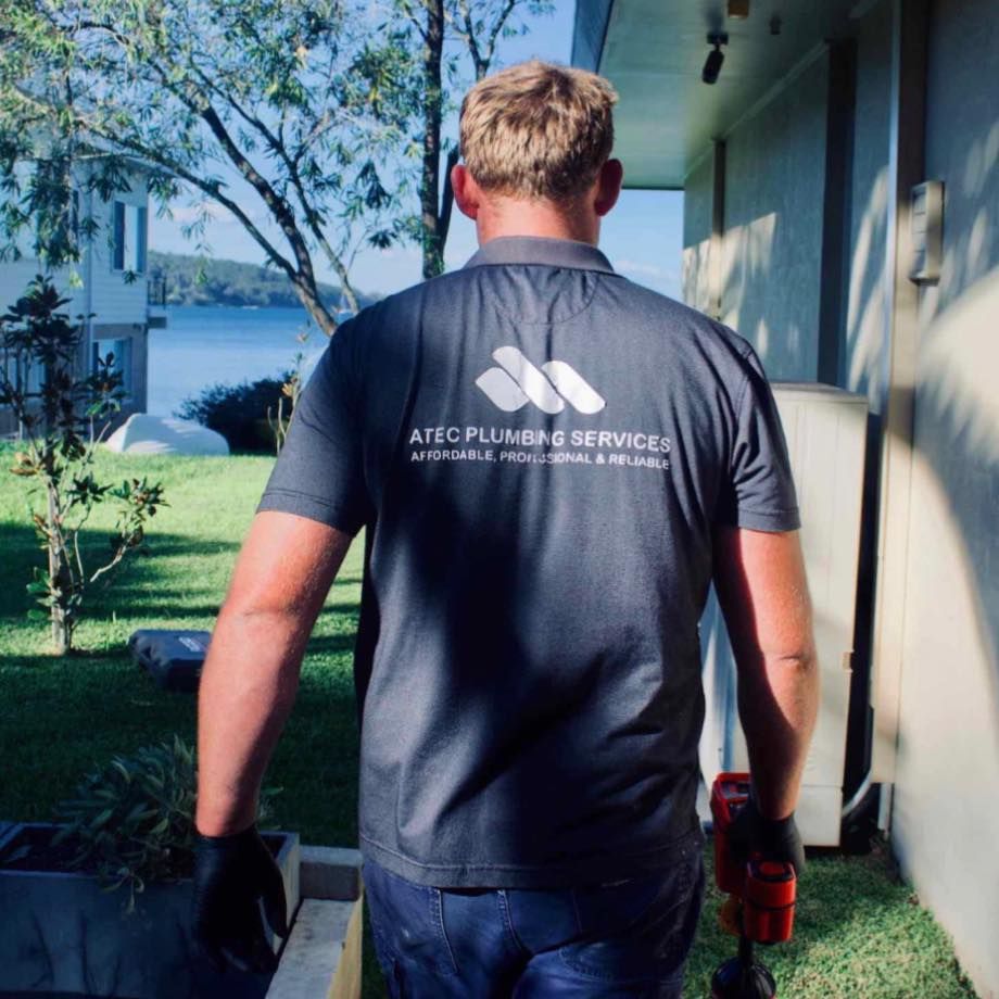 Plumber In Dark Work Shirt Walking Toward A House — ATEC Plumbing Services in Coal Point, NSW