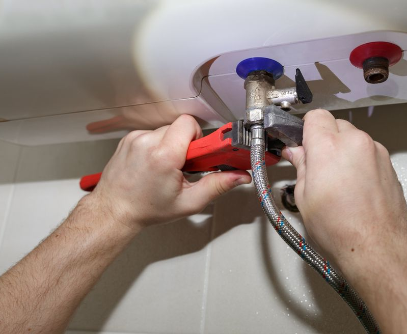 A Person Uses A Red Wrench To Tighten A Metal Hose — ATEC Plumbing Services in Morisset, NSW