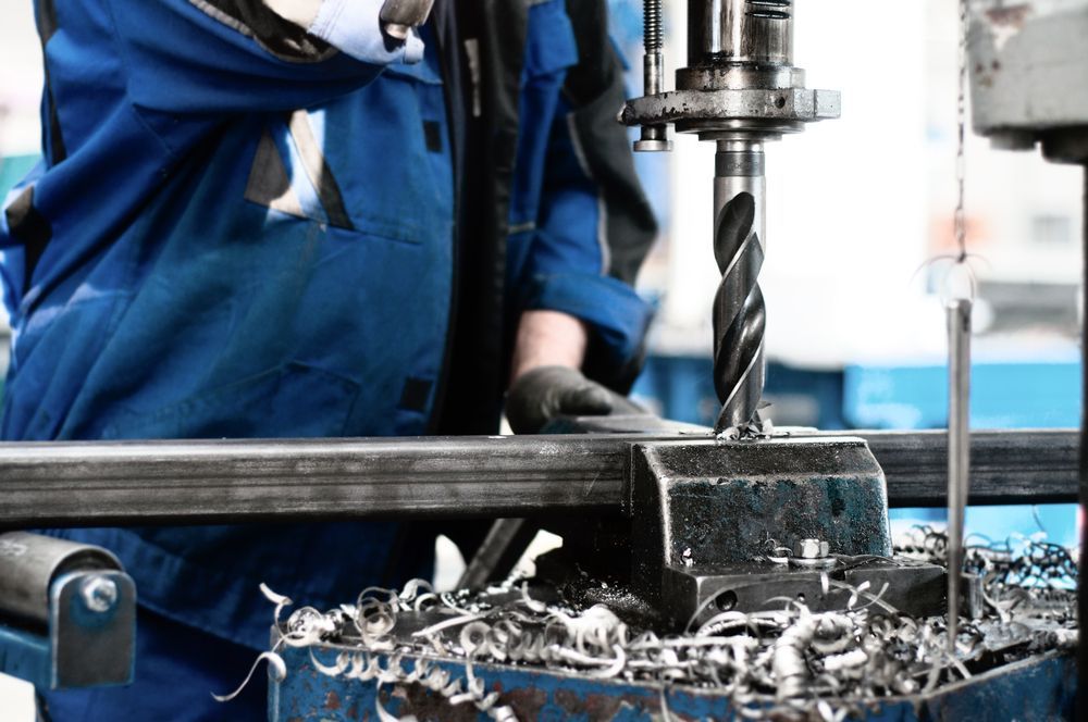 A Man Is Working On A Machine In A Factory — Absolute Steel Fabrication & Welding In East Wagga Wagga, NSW