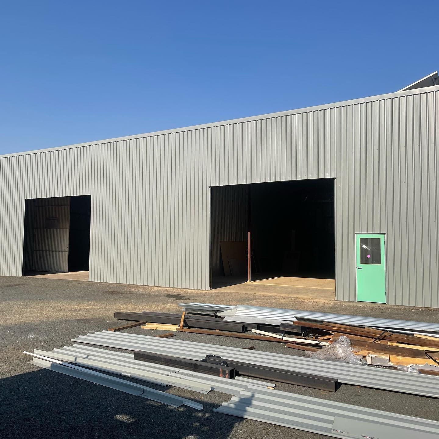 Gray Corrugated Metal Warehouse With Open Bays and a Green Door — Absolute Steel Fabrication & Welding In East Wagga Wagga, NSW