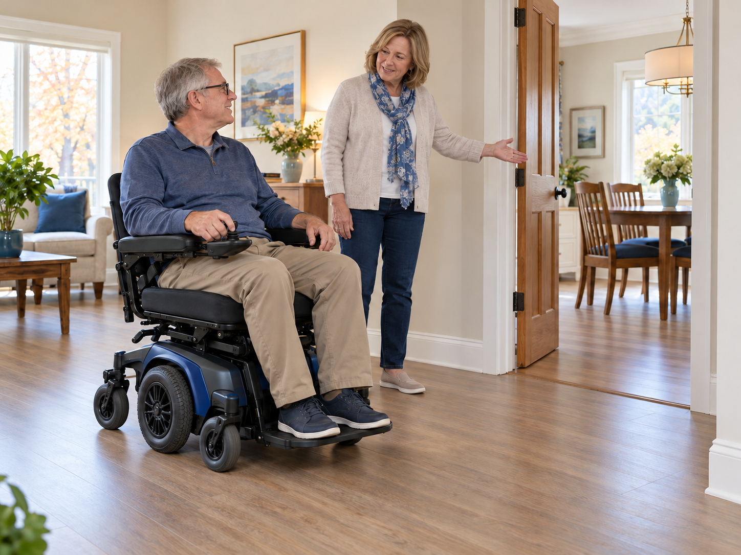 Adult seated in a compact power wheelchair discussing doorway clearance with a family member at home