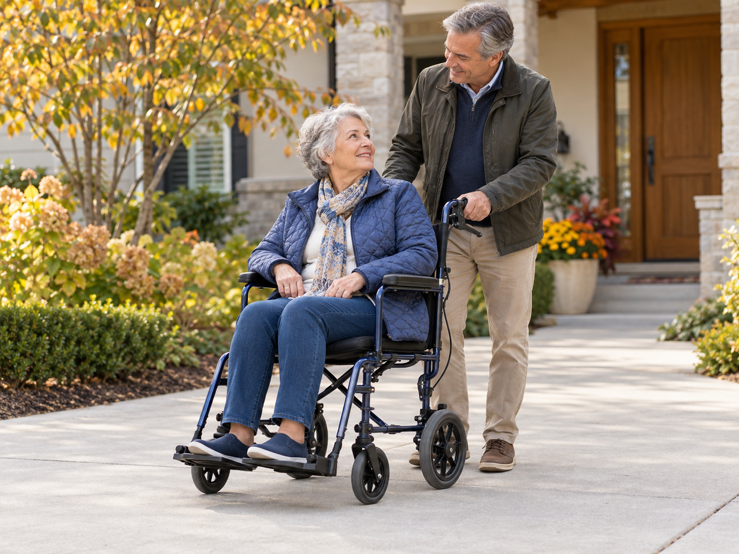 Adult seated in a transport chair with a family member beside the caregiver push handles