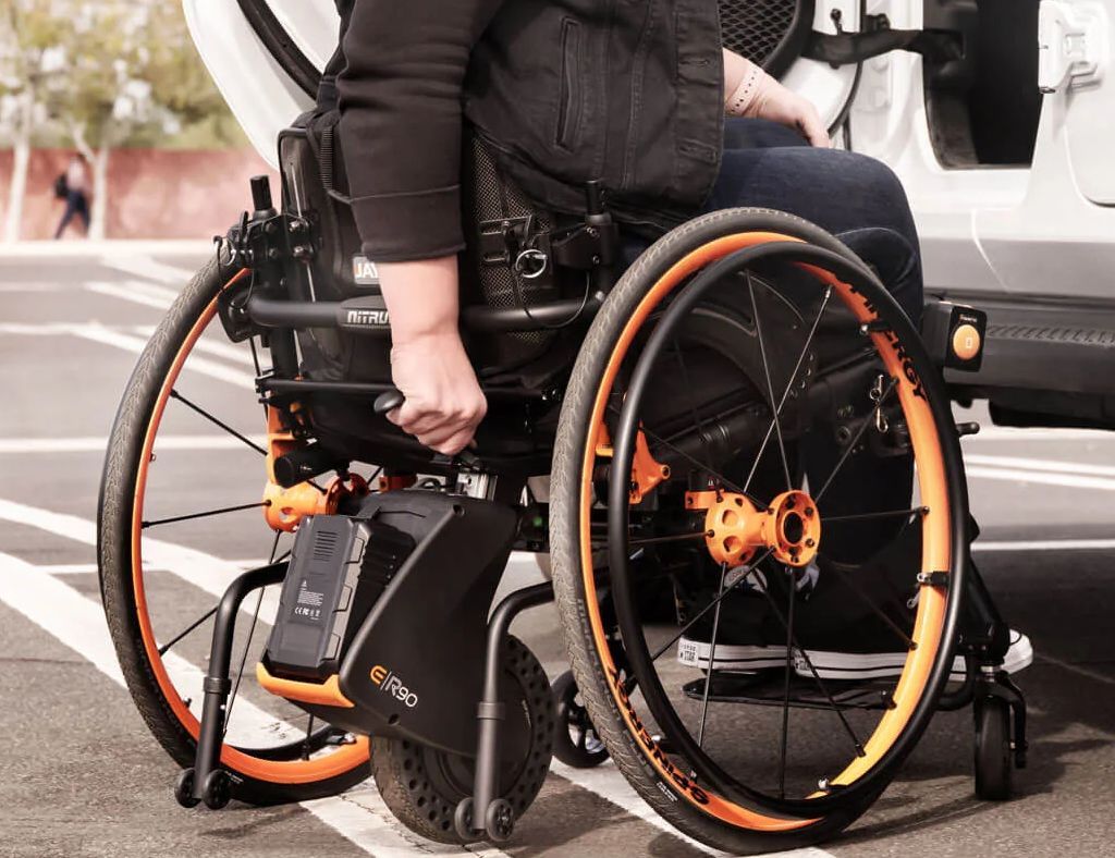Manual wheelchair user with a back mounted power assist attachment