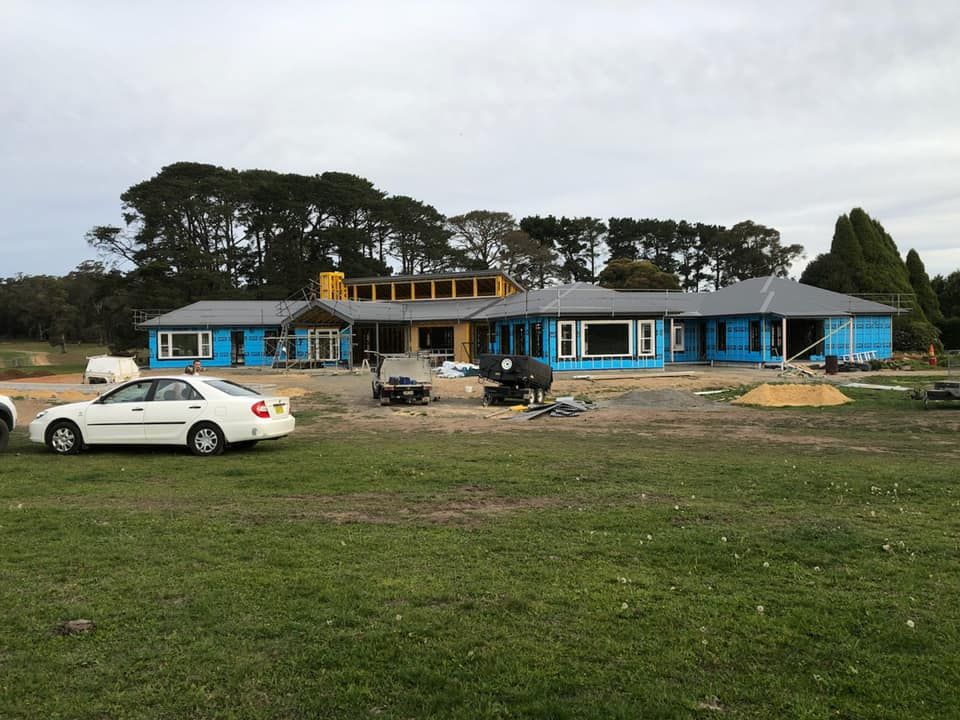A White Car Is Parked in Front of A Large House Under Construction — GMT Builders Pty Ltd in Mittagong, NSW