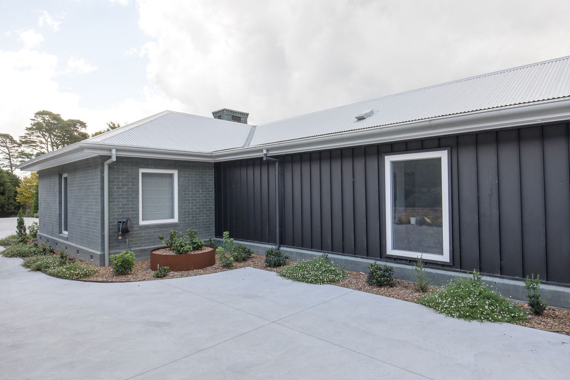 A large house with a black siding and a white roof — GMT Builders Pty Ltd in Nowra, NSW