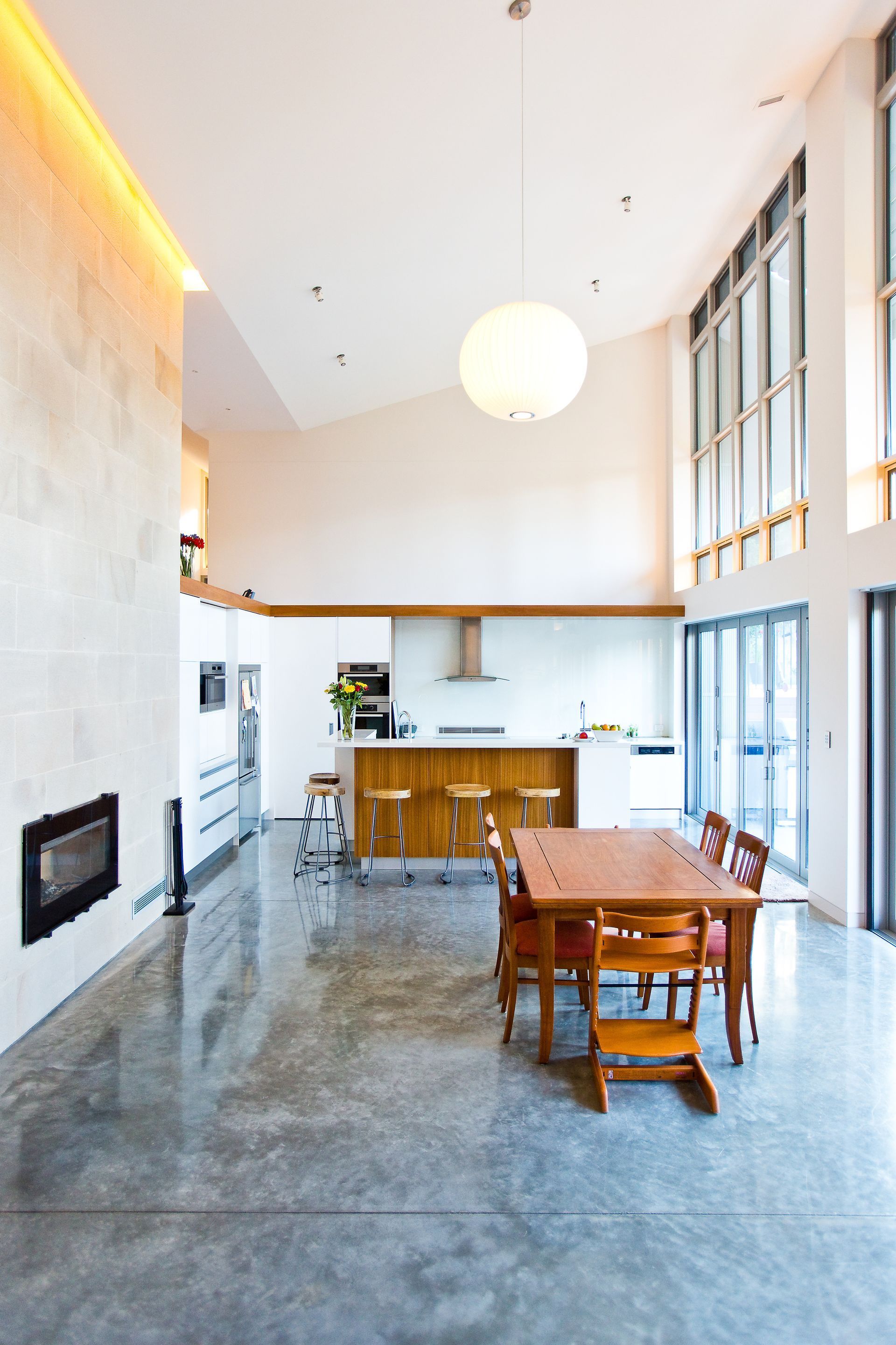 A Patio with Chairs and A Table Is Visible Through a Sliding Glass Door — GMT Builders Pty Ltd in Berrima, NSW