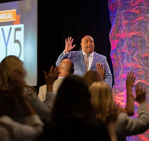 A man in a suit and tie is giving a speech to a crowd of people.