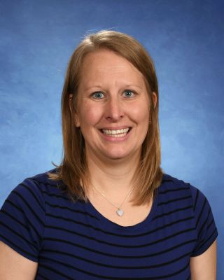 A woman in a blue shirt is smiling in front of a blue background.