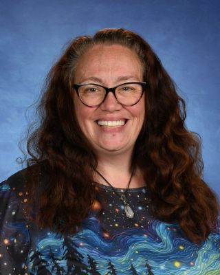 A woman in a blue shirt is smiling for the camera. This is Mrs. Stacy Clausing.