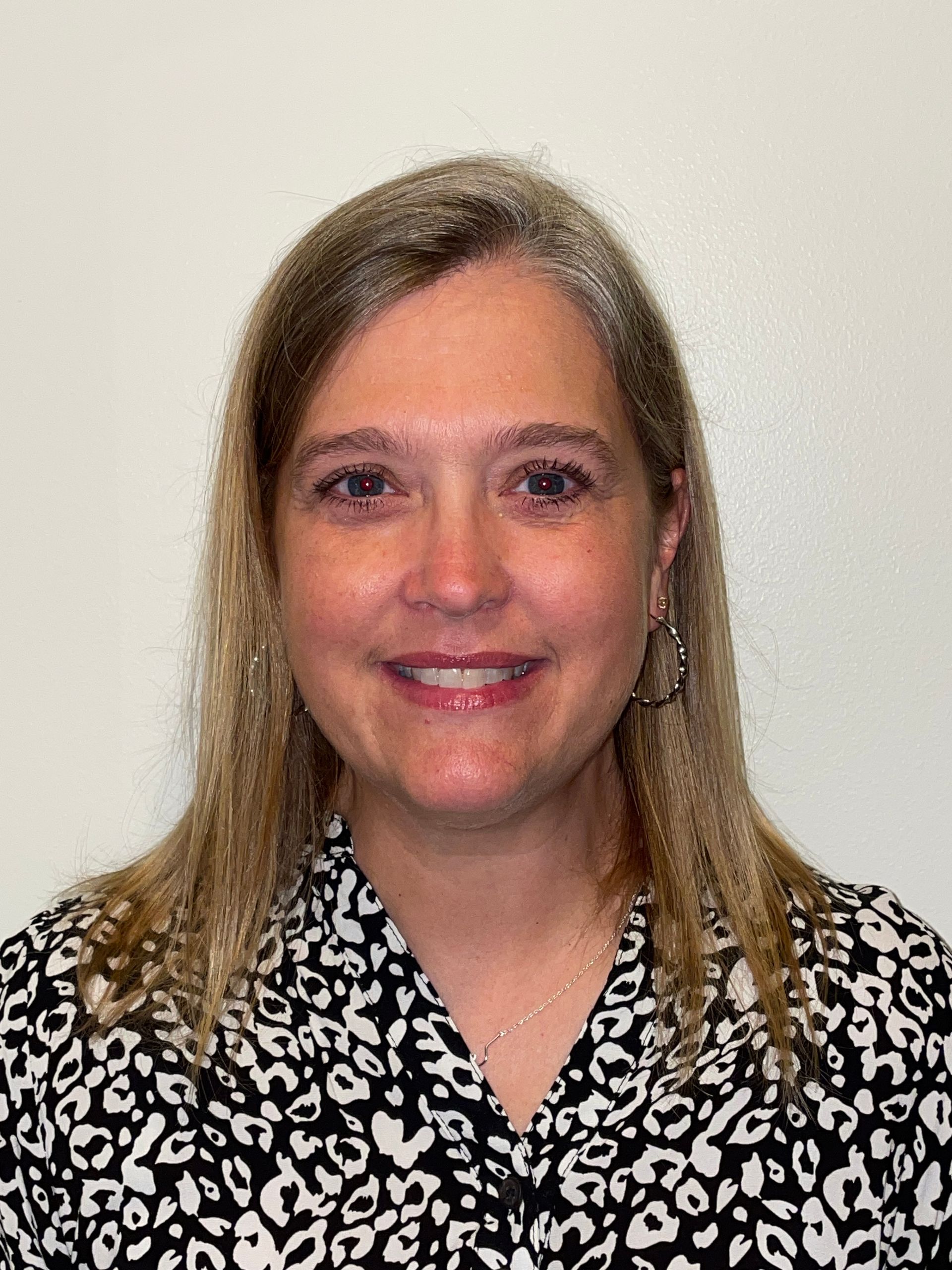 A woman in a leopard print shirt is smiling for the camera.