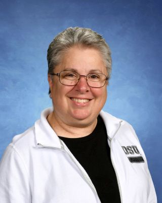 A woman wearing glasses and a white jacket with osu on it