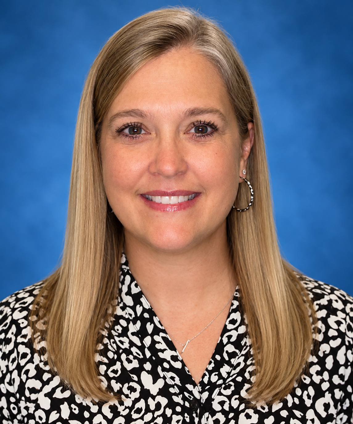 A woman in a leopard print shirt is smiling for the camera.