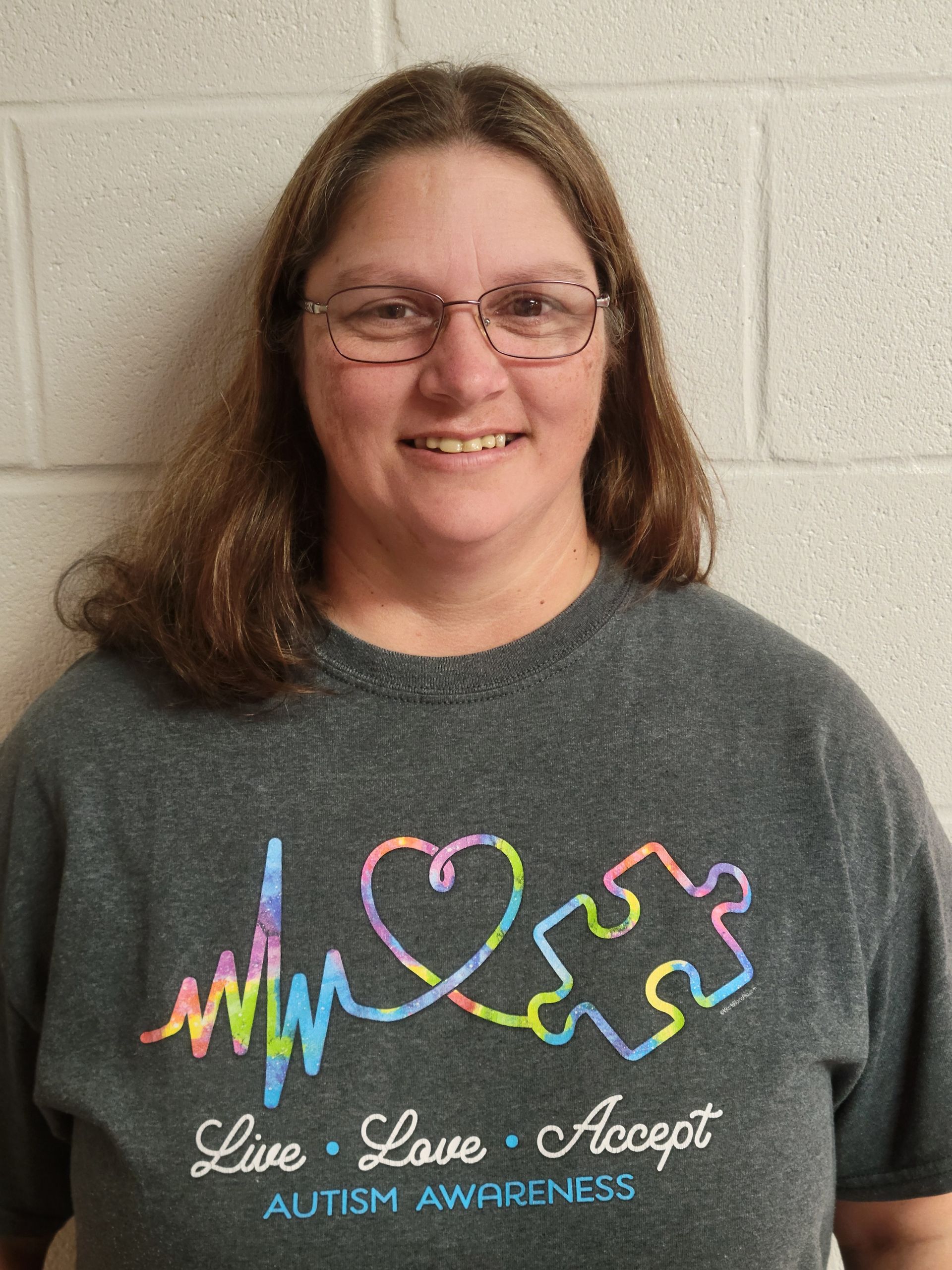 A woman wearing a t-shirt that says live love accept autism awareness