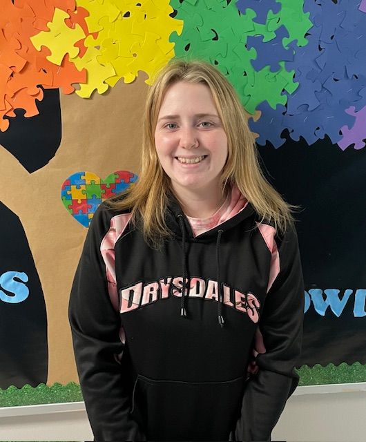A woman in a black and yellow floral shirt is smiling for the camera.