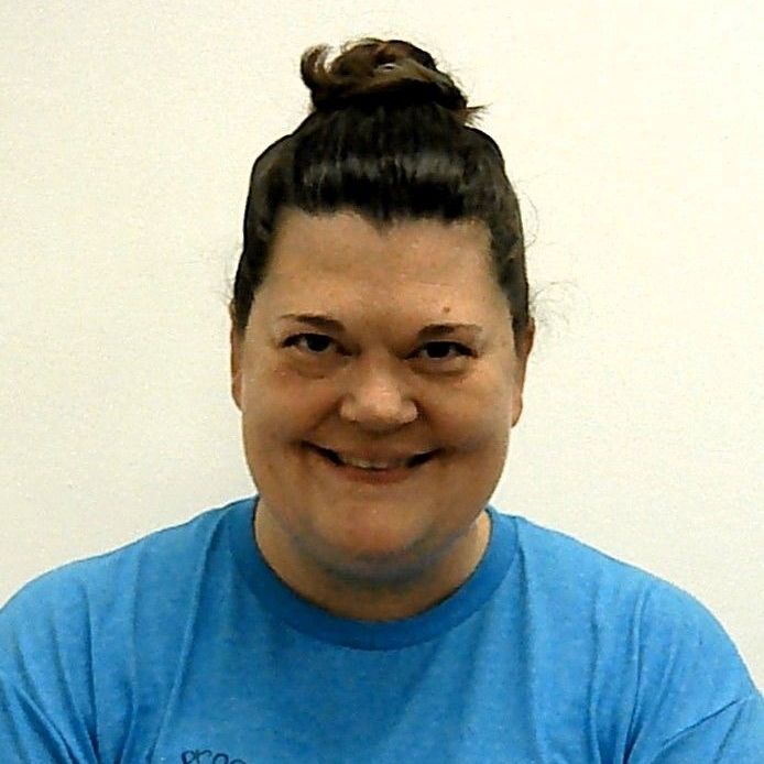 A woman in a blue shirt is smiling for the camera